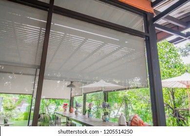 Coffee Shop Is A Glass Room With Blind, Curtain, Roller, Shade, Shutter Protected Sunlight And Green Garden Outside.