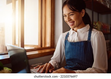 Coffee Shop Owner On Laptop, Startup And Woman From Singapore Typing Email Or Planning Menu Online. Happy Manager At Cafe Or Restaurant Reading Review On Shop Social Media Or Positive Sales Report.