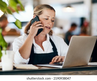Coffee Shop Owner On A Phone Call While Working Online On Her Laptop Inside A Local Cafe Store. Contact Us, Learn About Us And Talk To Our Baristas, Managers And Small Startup Business Entrepreneurs