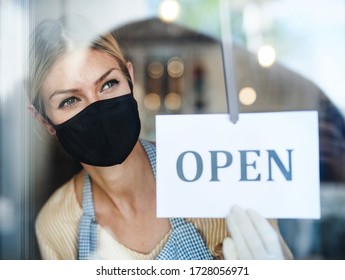 Coffee shop woman owner with face mask, open after lockdown quarantine.