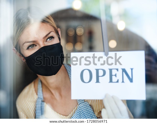 Coffee shop woman owner with face mask, open\
after lockdown\
quarantine.