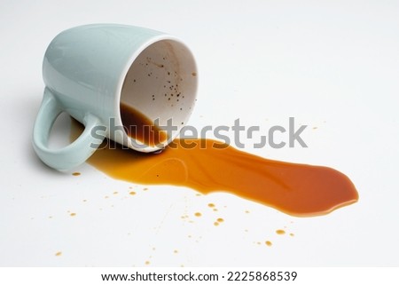 Coffee spill from a blue cup on white background, soft focus close up