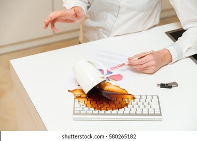 Coffee spilled over modern keyboard and self made sheet of "sales report"