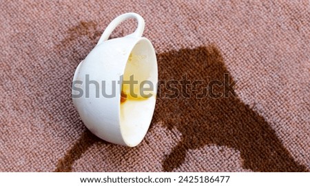 Coffee spilled from white cup on the carpet