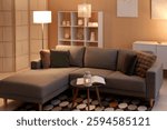 Coffee table with lantern, cozy sofa and glowing lamps in interior of living room