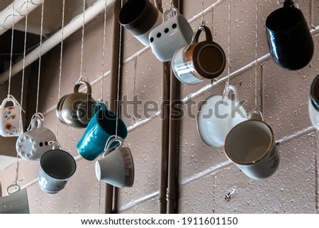 Coffee or tea ceramic mugs dangling from strings at a cute retro cafe in the wintertime. 