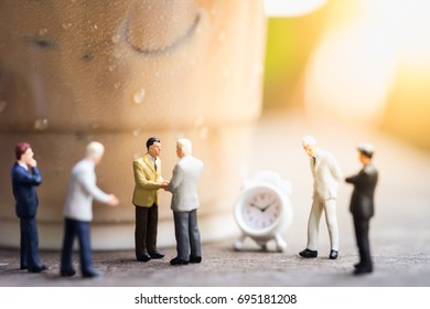 Coffee, Time And Business Cooperation Concept. Group Of Businessman Miniature People Figures Meet And Hand Shake Close To A Plastic Cup Take Away Of Iced Coffee Latte With Mini Clock Toy.