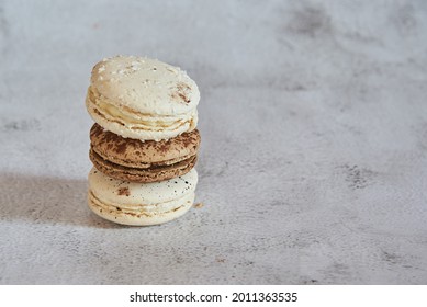 Coffee and vanilla macaroon are stacked in a pyramid on a light gray background. Copy space for text, design.
