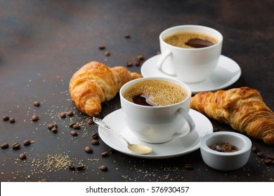 Coffee white cup, croissants on dark retro background, selective focus. Breakfast concept