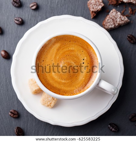 Coffee in white cup on black slate background. Top view.