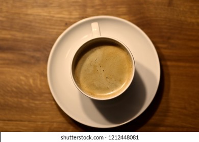 Coffee in a white cup with saucer on wood-table (bird's-eye view)