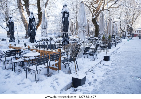 coffees shops tables chairs in\
the snow ice in  winter season in Ioannina city Greece  whtie\
color
