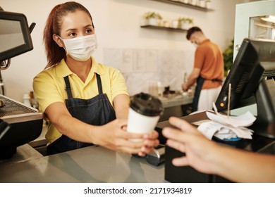 Coffeeshop Barista Wearing Medical Mask When Selling Cup Of Take Out Coffee To Customer