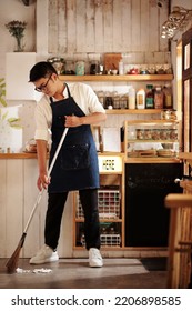 Coffeeshop Owner Sweeping Floor Before Opening In The Morning