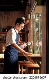 Coffeeshop Worker Wiping Surfaces With Disinfecting Detergent Before Opening