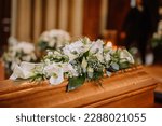 A coffin decorated with many flowers and candles in a beautiful church, ceremony