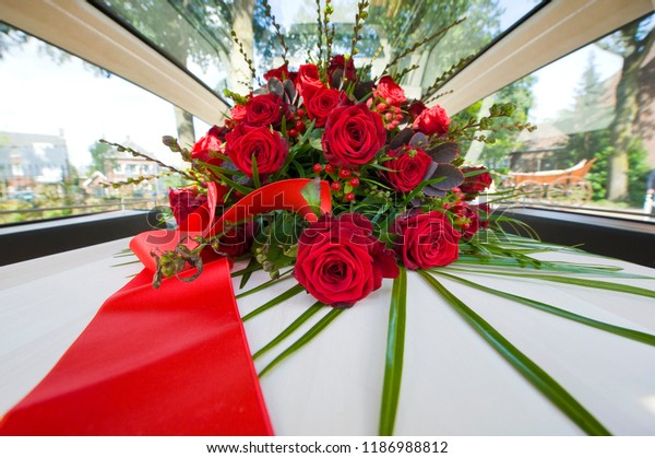 A\
coffin with a flower arrangement in a funeral\
car