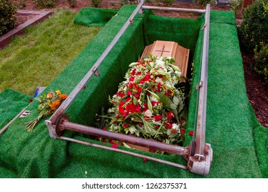 Coffin With A Lot Of Flowers In Grave While Funeral