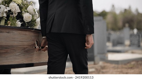 Coffin, hands and man walking at funeral ceremony outdoor with pallbearers at tomb. Death, grief and person carrying casket at cemetery, graveyard or family service of people mourning at windy event