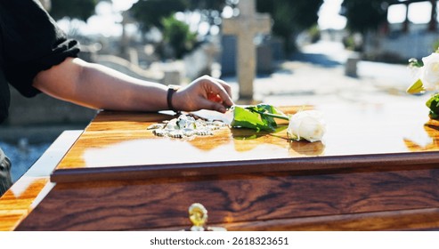 Ataúd, rosa y mujer en el funeral con respeto, dolor o pérdida en el servicio familiar para el entierro. Mano, luto y persona femenina con flor blanca en el ataúd para el recuerdo en el memorial en el cementerio.