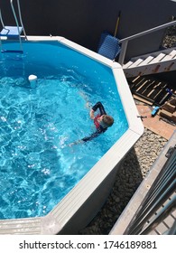 Coffs Harbour, NSW / Australia - Oct 23rd 2019 - A High Angle View Of A Boy Swimming In An Above Ground Pool With A Rash Shirt On 