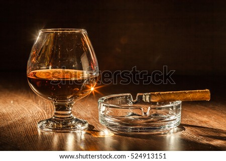 Cognac drinks with cigars on dark background