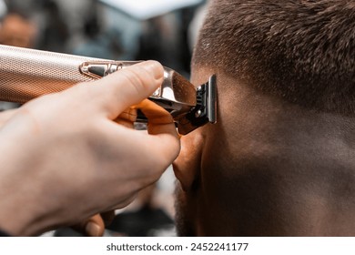 Coiffeur shaves client hair with electrical trimmer in modern barbershop closeup. Barber does elegant haircut contour in beauty salon - Powered by Shutterstock