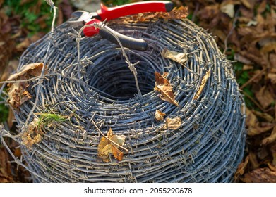 A Coil Of Barbed Wire And A Cutter On A Top, Outdoor Closeup