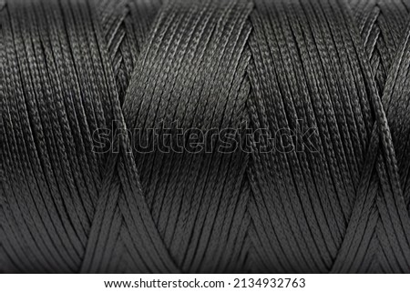 A coil of black thread. Spool of colored threads on a white background. Waxed sewing thread for leather crafts.