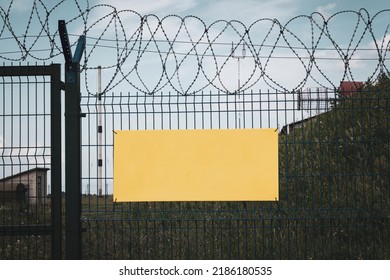 Coiled barbed wire fencing against a blue sky background. a yellow sign on the fence wall. Empty space for the text. Restricted area of the airport
