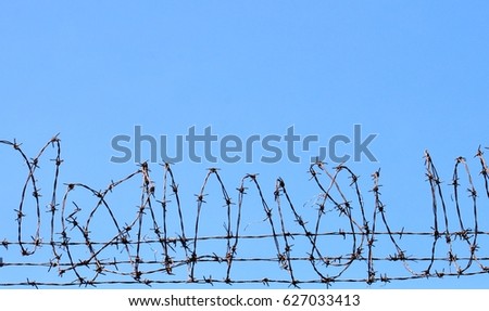 Coiled barbed wire fencing against a blue sky background