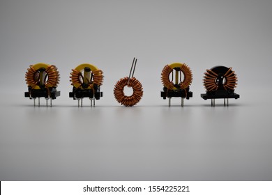 Coils With Magnetic Core And Copper Winding Isolated On White Background. Magnetic Inductors Ferrite Core Common-Mode EMI Suppression. Choke Coil Used For EMC Test. Toroidal Coil Inductor.