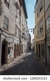 Coimbra, Portugal - September 7, 2018: A Cobblestone Alleyway Leading Down Between Typical Buildings With Fado Bar And Wall And Hanging Street Decorations In Coimbra Portugal