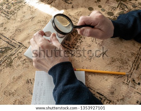 The Coin Evaluator. The collector of coins. The man considers ancient coins.