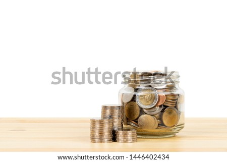 Coin glass jar container and stack on wooden desk, saving concept, on white background