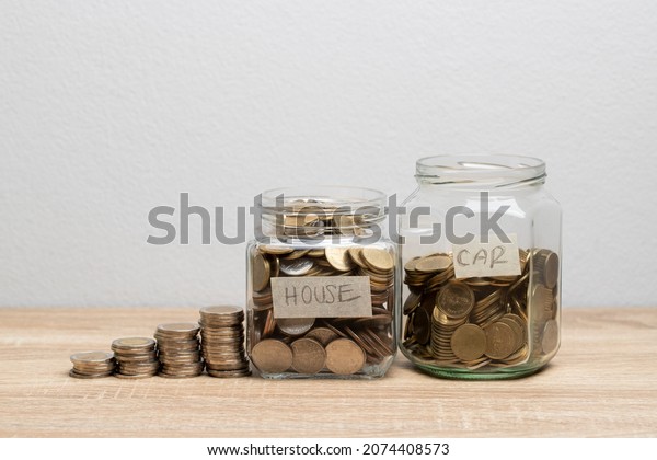 Coin in a glass jar\
for saving money on the brown table with money stack and copy space\
for financial concept