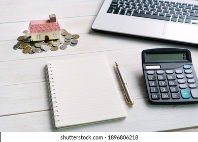 coin with house model and notebook for copy space, calculator and computer laptop, savings plans for housing financial concept, close up