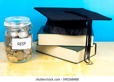 Coin In The Jar With Text RESP(Registered Education Savings Plan ), Books And Graduation Hat On Wooden Background.