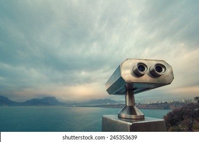Coin Operated Binocular viewer next to the waterside promenade in Antalya looking out to the Bay and city. Landscape with beautiful cloudy sky, sea and mountains.. - Shutterstock ID 245353639