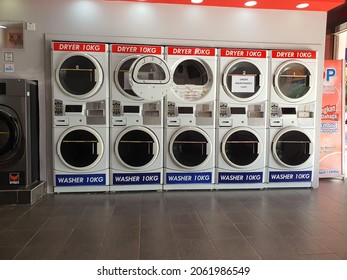 Coin Operated Laundry Service. White Stackable Dryer And Washer For 10 Kg Loading Cloth. Front Round Loading With Clear Viewing Window. User Friendly Design. Clean Brown Tiles. Malaysia. October 2021