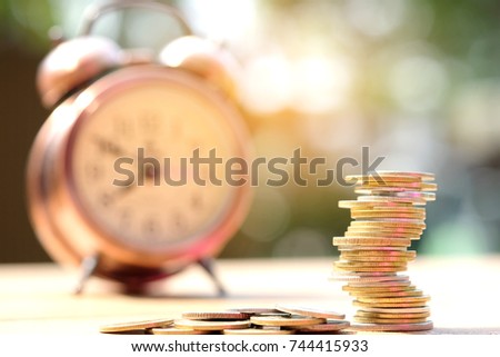 Coin pile on background clock, financial Concept saving money , investing and spending time.