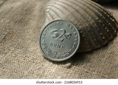 Coin and shell on linen fabric. Croatian 2 Kune coin obverse.