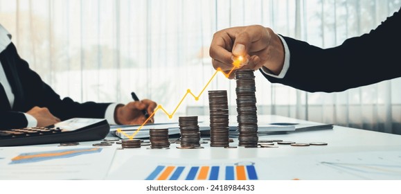 Coin stack with digital graphic indicator symbolizing business investment and economic growth. Businessman doing financial planning to achieve financial goal and contribute to profit. Shrewd