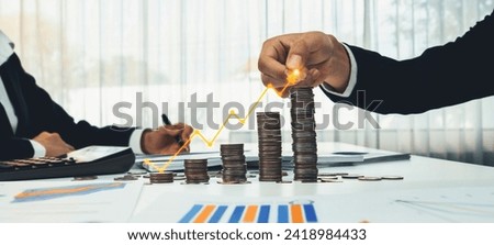 Coin stack with digital graphic indicator symbolizing business investment and economic growth. Businessman doing financial planning to achieve financial goal and contribute to profit. Shrewd