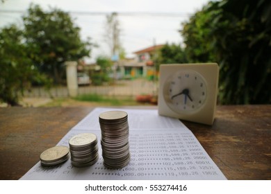 Coin stack on bank statement with clock and house blur background, investment saving concept