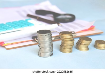 Coin Stack On Table With Calculator Spreadsheet Paper Chart Magnifying Glass, Concept Of Wealth Growth And Money Saving