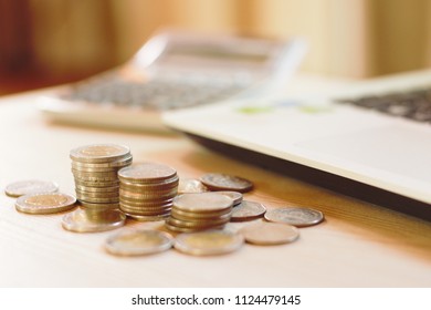 Coin stacks on wood table with calculator and computer laptop notebook. Business and financial concept.