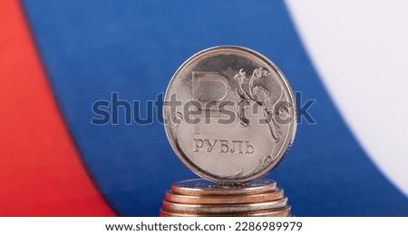 Coin with the symbol of the Russian ruble on the background of the Russian flag
