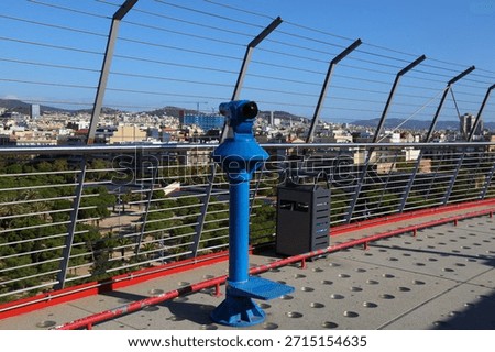 Coin viewer binoculars at a viewpoint overlooking Barcelona cityscape with Parc de Joan Miro.