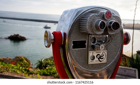 Coin-operated Viewfinder In Focus On The Right Side Of The Photo, While The Left Side Is Blurry And Shows The Ocean.